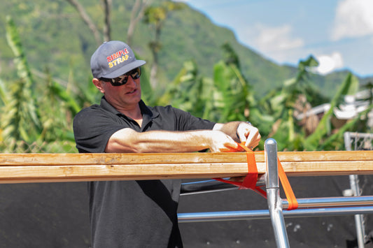 Person fester planker med Simple Strap stropp på takstativ på bil.