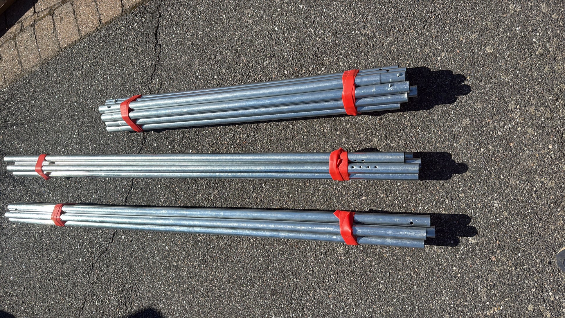 Galvaniserte metallrør buntet sammen med røde Simple Strap stropper.